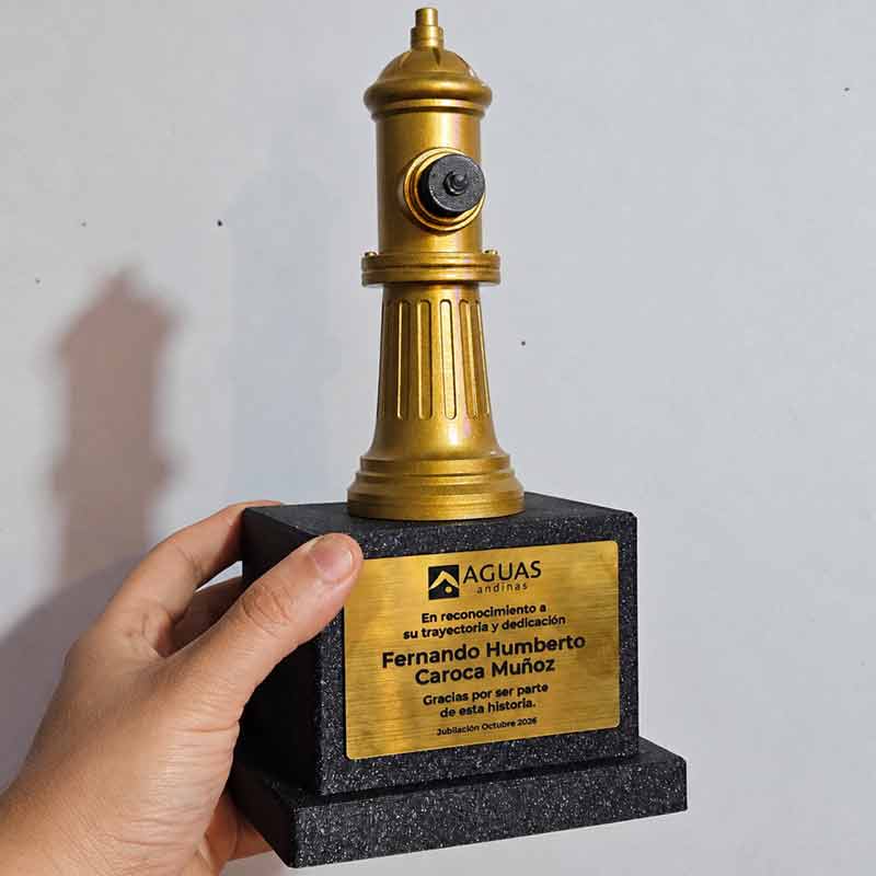 Galvano corporativo personalizado para Aguas Andinas, con figura dorada y placa de reconocimiento por trayectoria laboral y jubilación, fabricado en Chile.