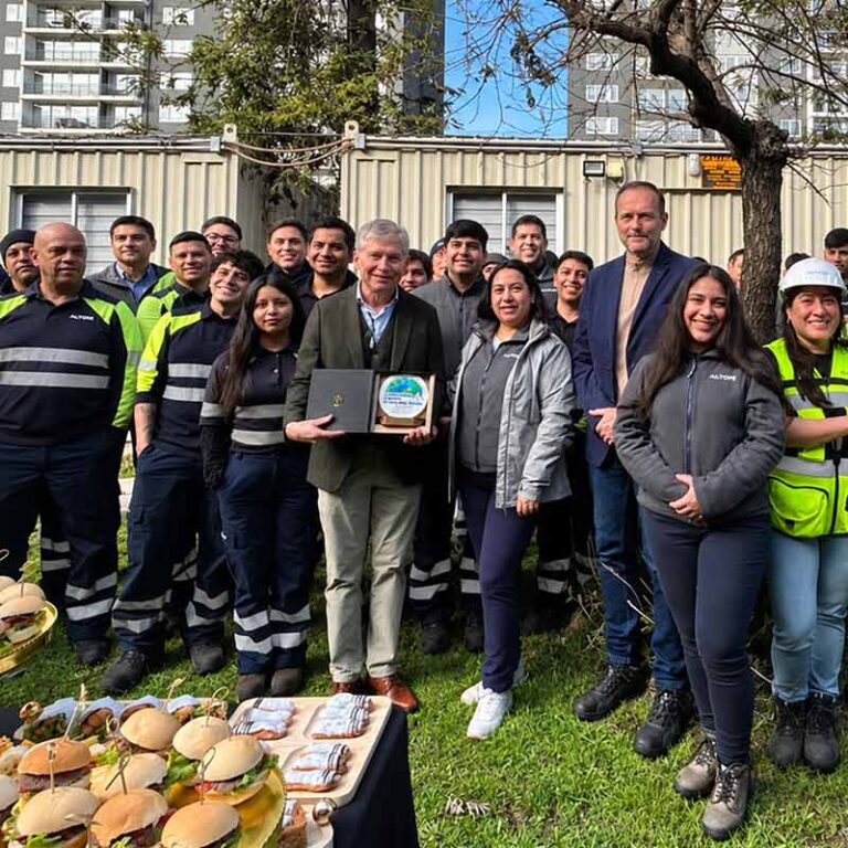 Equipo de trabajadores reunidos durante una ceremonia de reconocimiento corporativo, con entrega de un galvano conmemorativo.